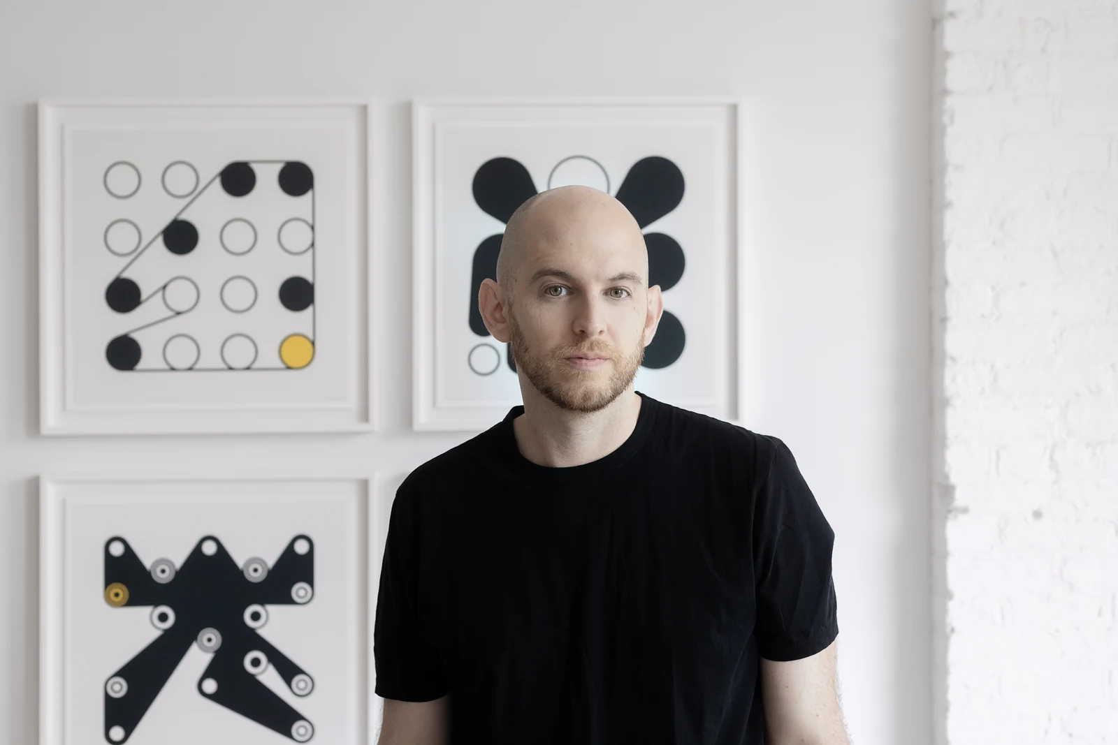 Dmitri Cherniak standing in front of framed Ringers works.