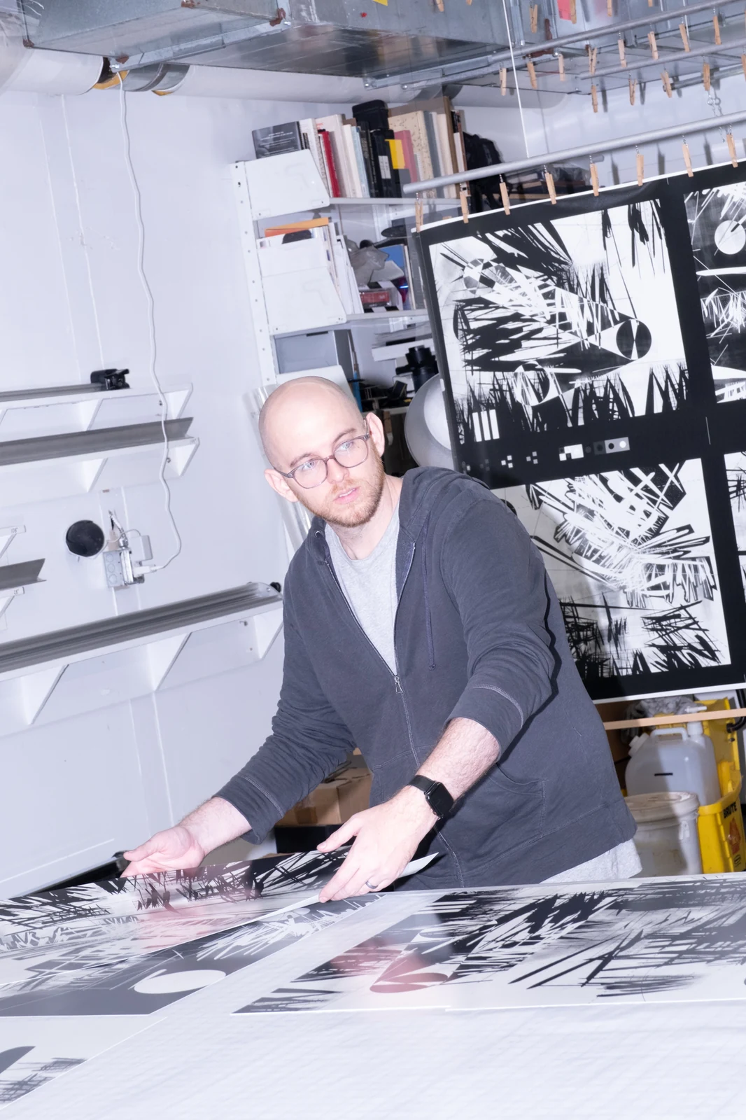 Dmitri Cherniak handling Light Years prints on a worktable, with more prints hanging behind him.