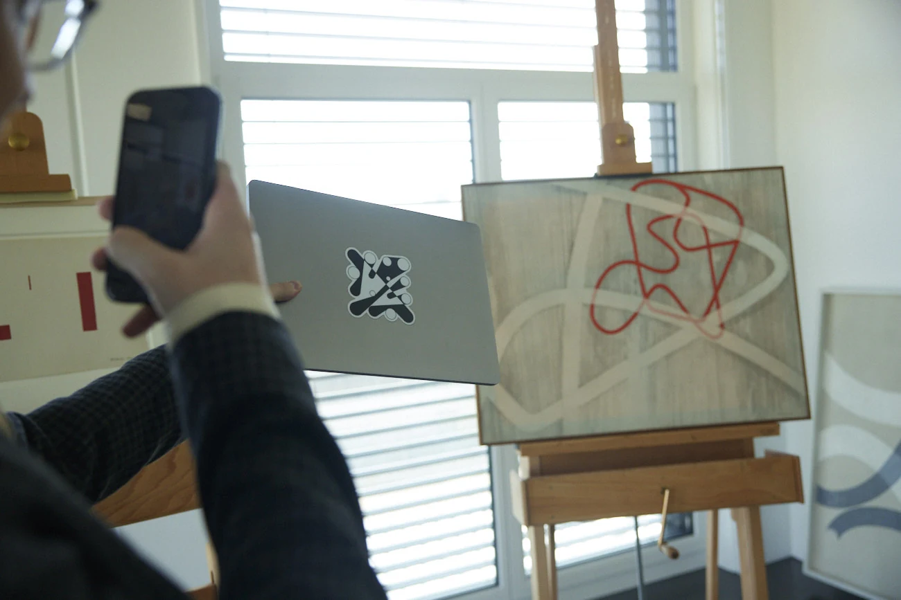 A laptop with a Ringers sticker held beside an artwork on an easel during research for Light Years.