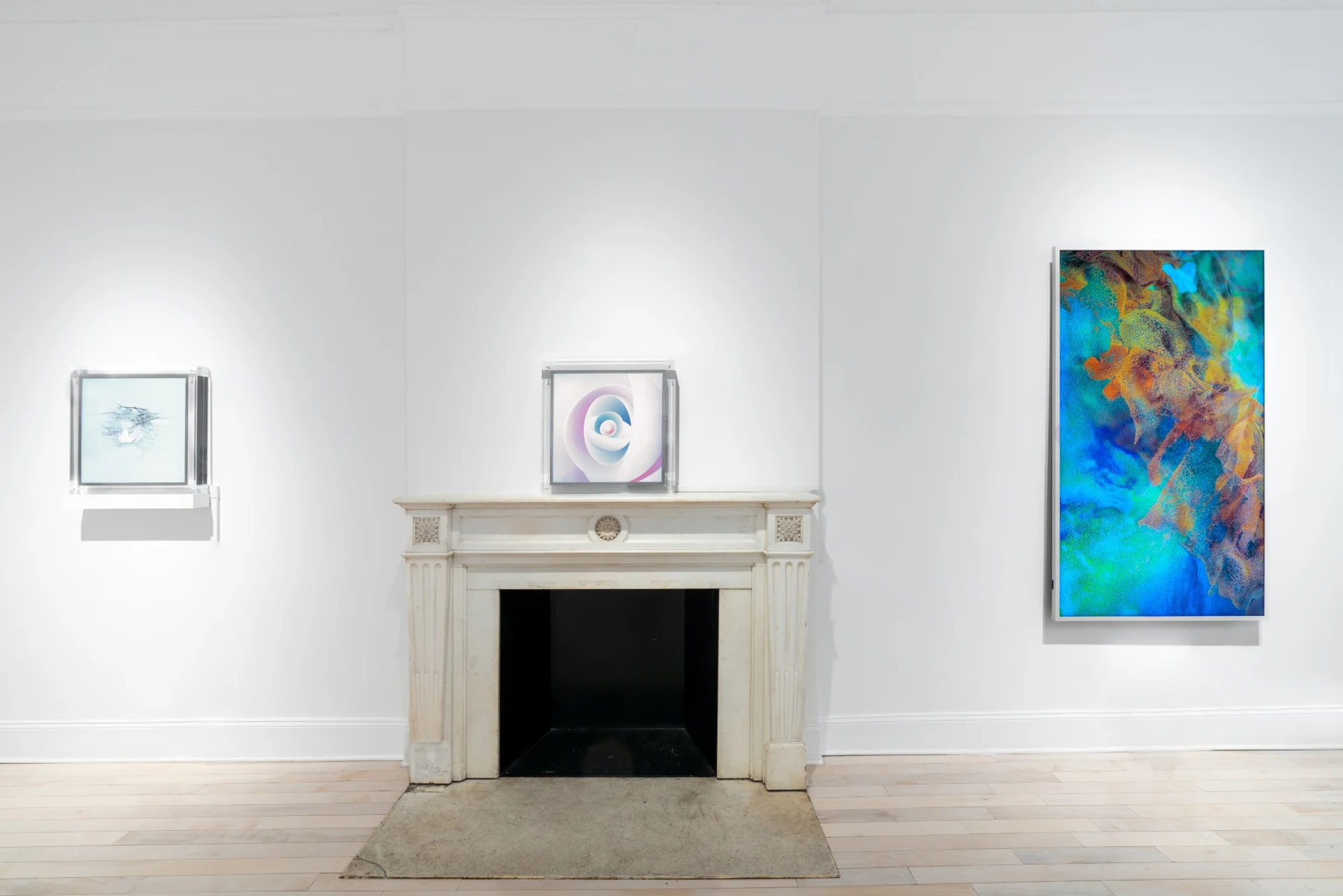 A breath of fresh pearls on a screen in a clear acrylic case, set on a white marble mantelpiece between two other screen-based works.