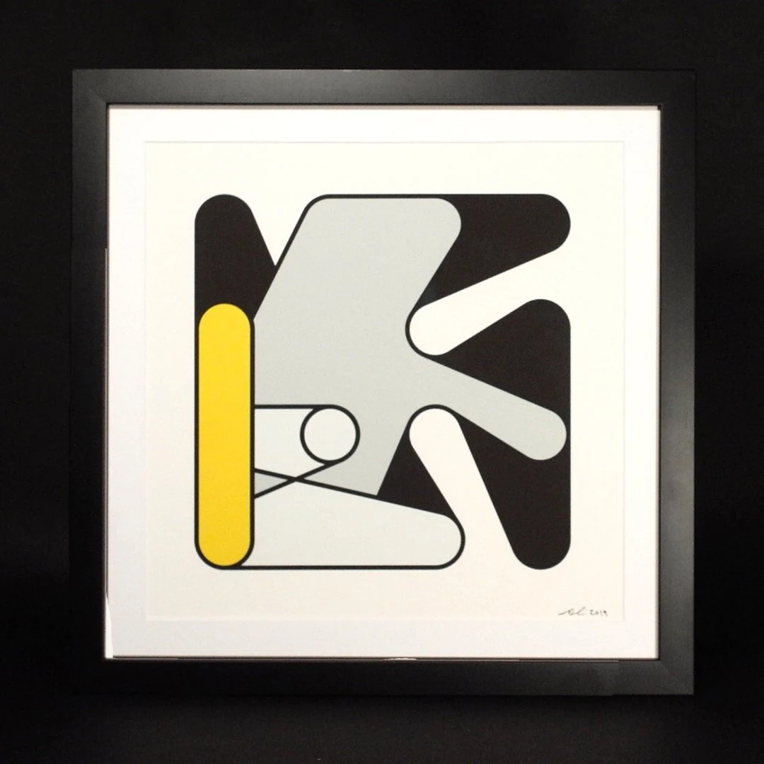 A framed print of Turbulent Figures, Step I, against a black background: overlapping charcoal and grey rounded forms with a tall yellow bar at the left, on a white sheet signed and dated 2019 at the lower right.