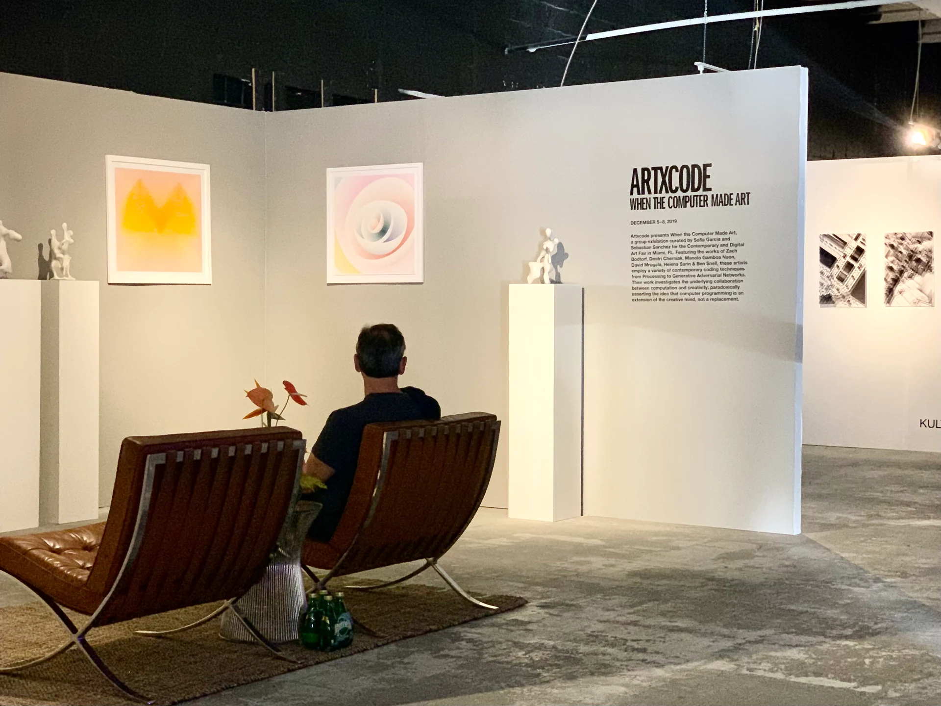 Installation view of artxcode’s presentation at Mana Wynwood, with framed works, sculptures, and exhibition wall text.
