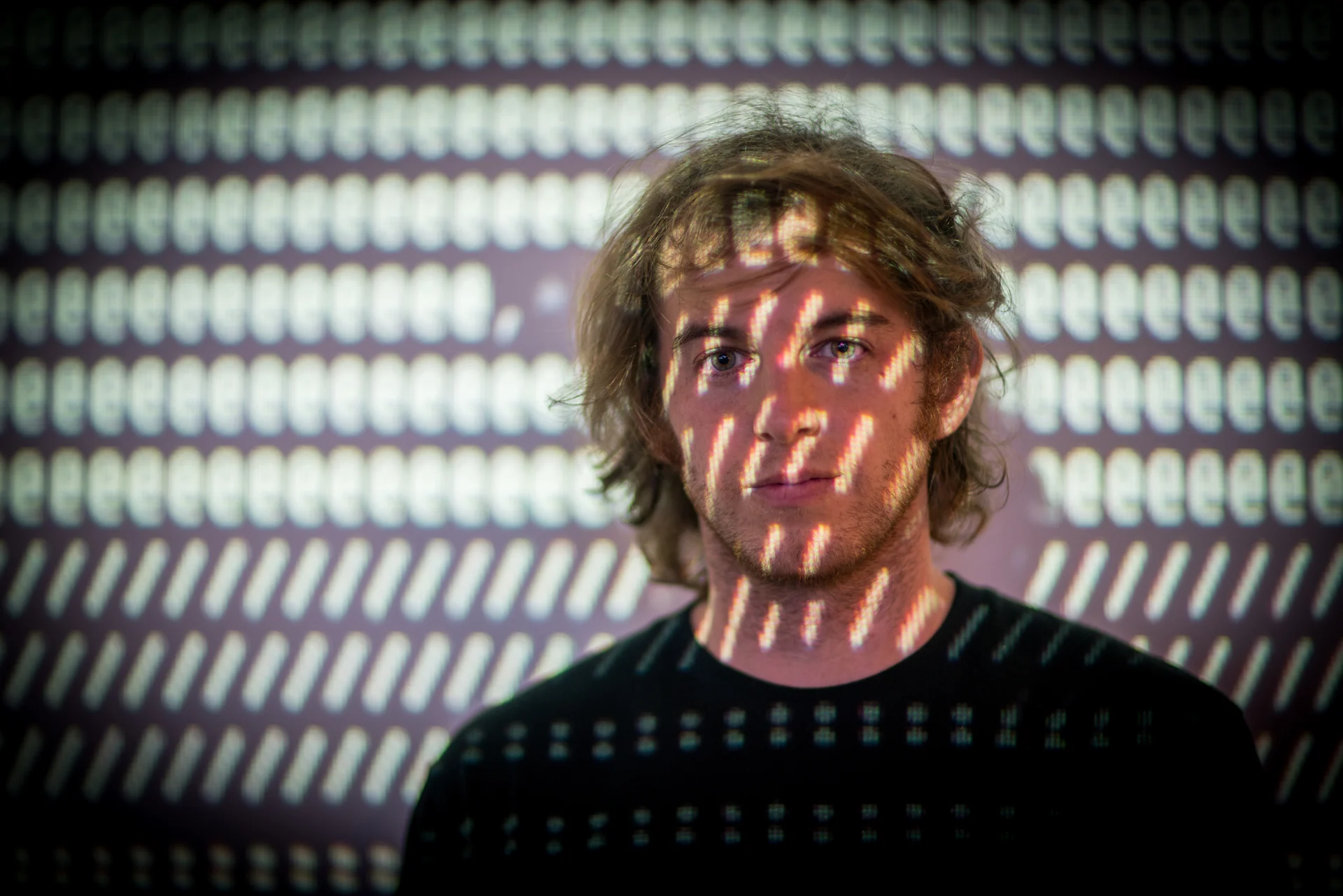 Projected characters falling across the artist’s face.