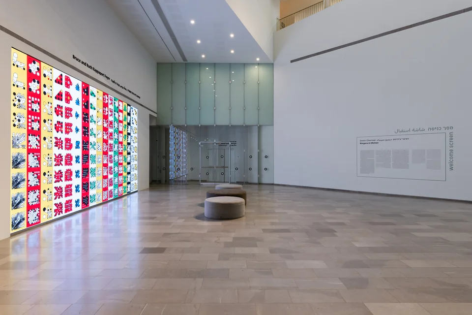 A wide view of the museum foyer with colorful Ringers on the left and exhibition wall text on the right.