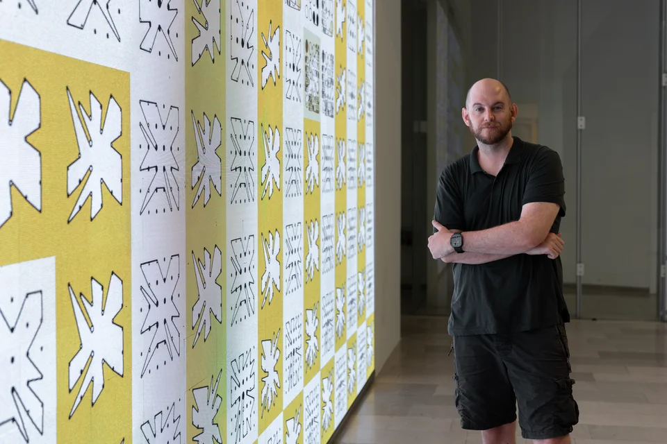 A person standing beside a close view of yellow and white Ringers on the screen.