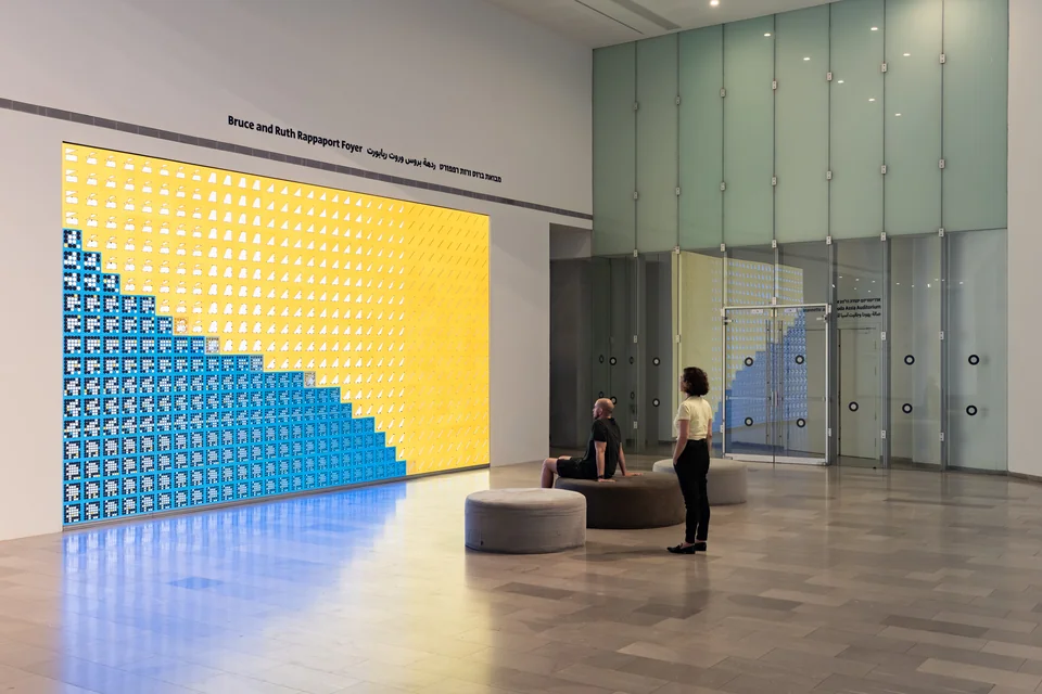Two people beside the installation displaying a diagonal field of blue and yellow Ringers.