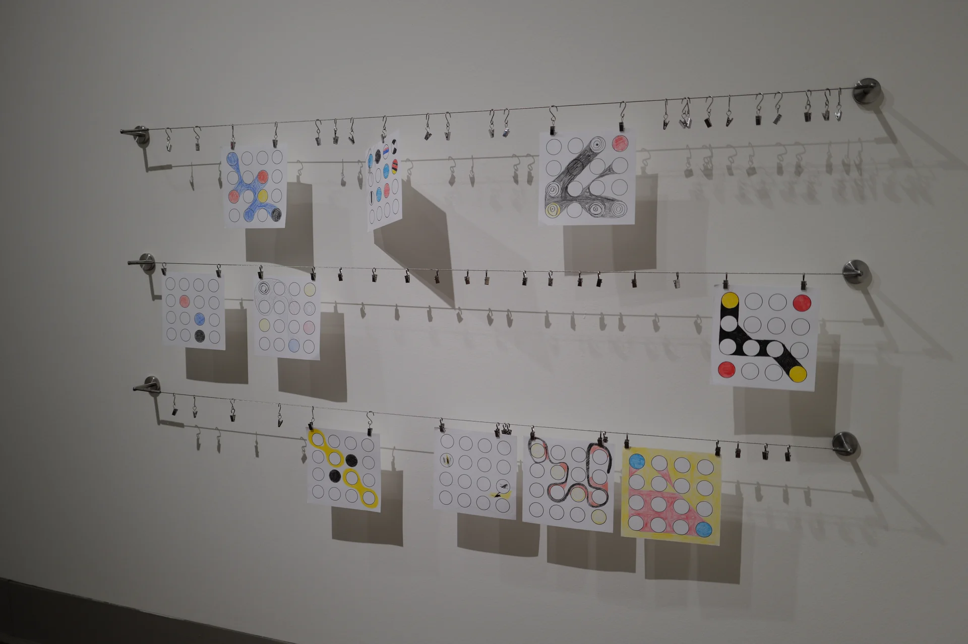 Hand-drawn and colored Ringers hanging from clips along three rows of wire.