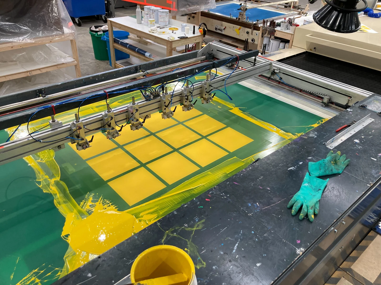 Yellow ink covers the four-by-four grid on a screenprinting press in the workshop.