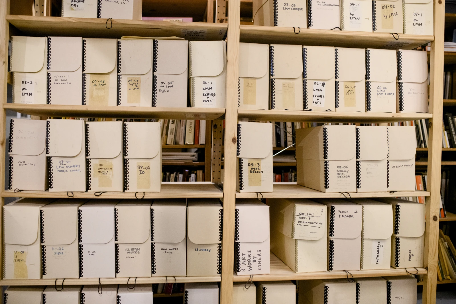 Labeled archival boxes arranged on wooden shelves in the László Moholy-Nagy archive.