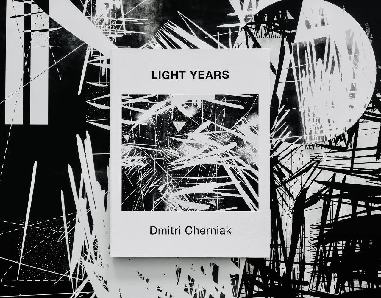 The Light Years book resting on black-and-white artworks from the series.