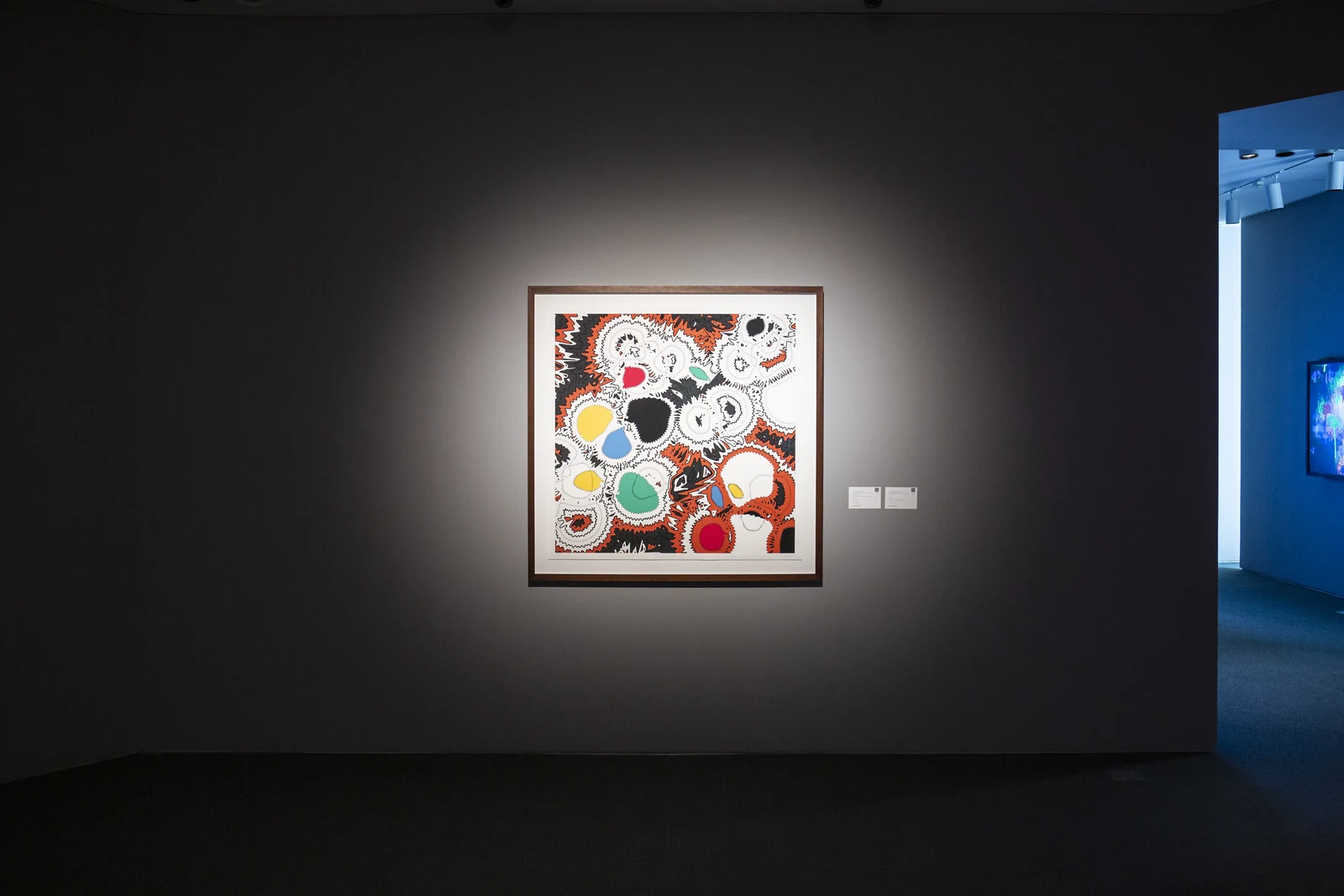 The framed print illuminated on a dark gallery wall at Sotheby’s.